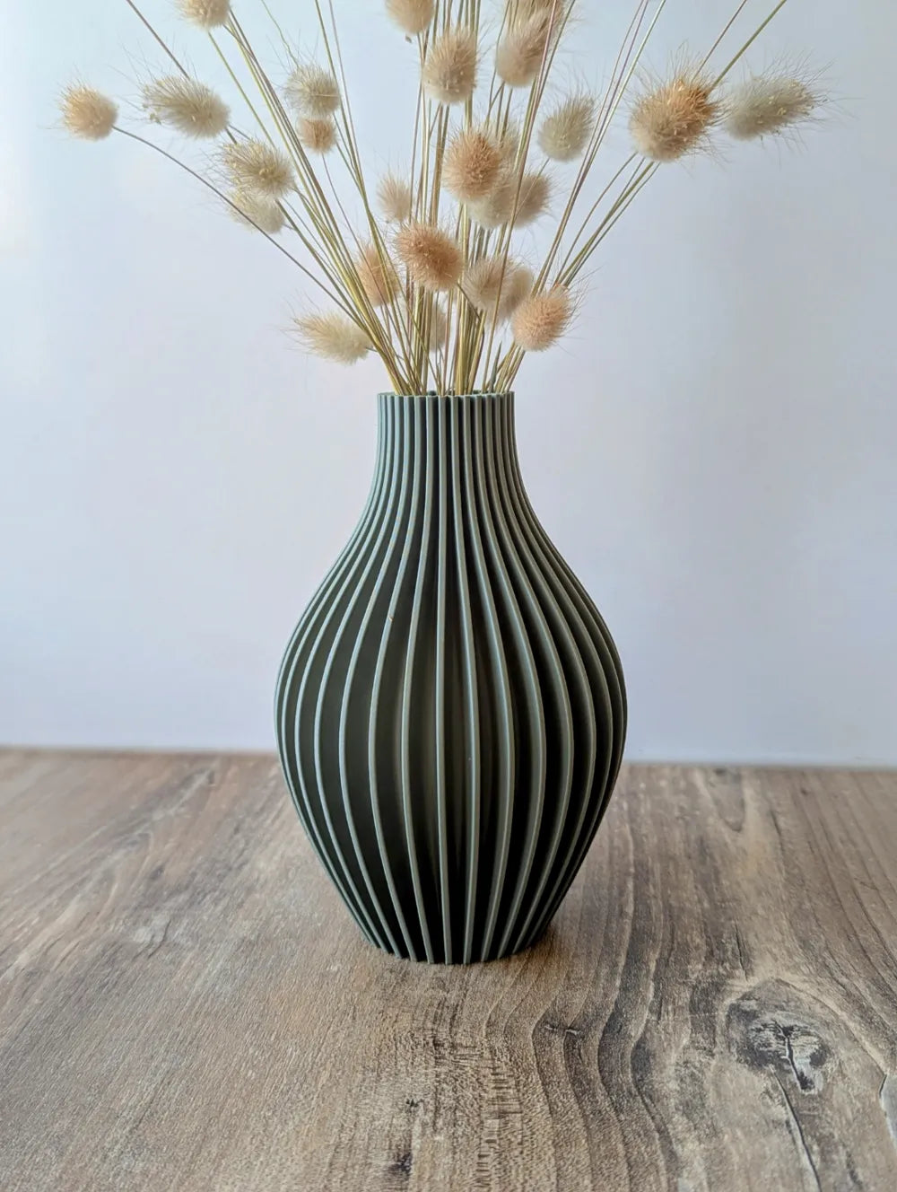 Vase cannelé vert foncé avec une composition de fleurs séchées