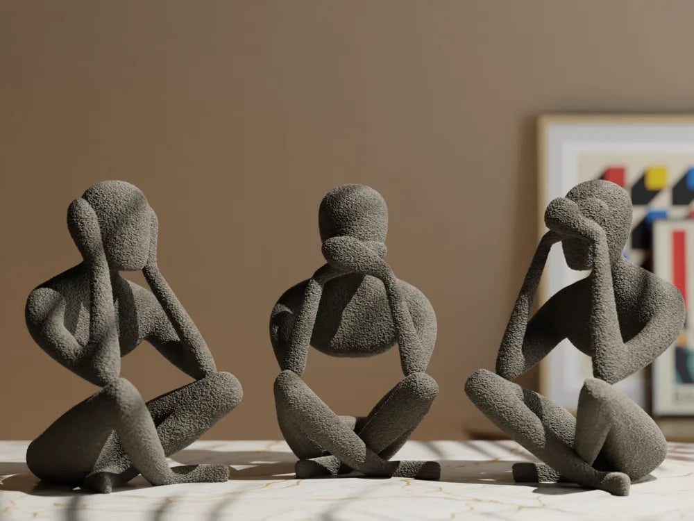 Trio de figurines penseur abstrait grises, vue de face sur table en marbre