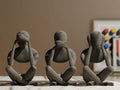 Trio de figurines penseur abstrait grises, vue de dos sur table en marbre