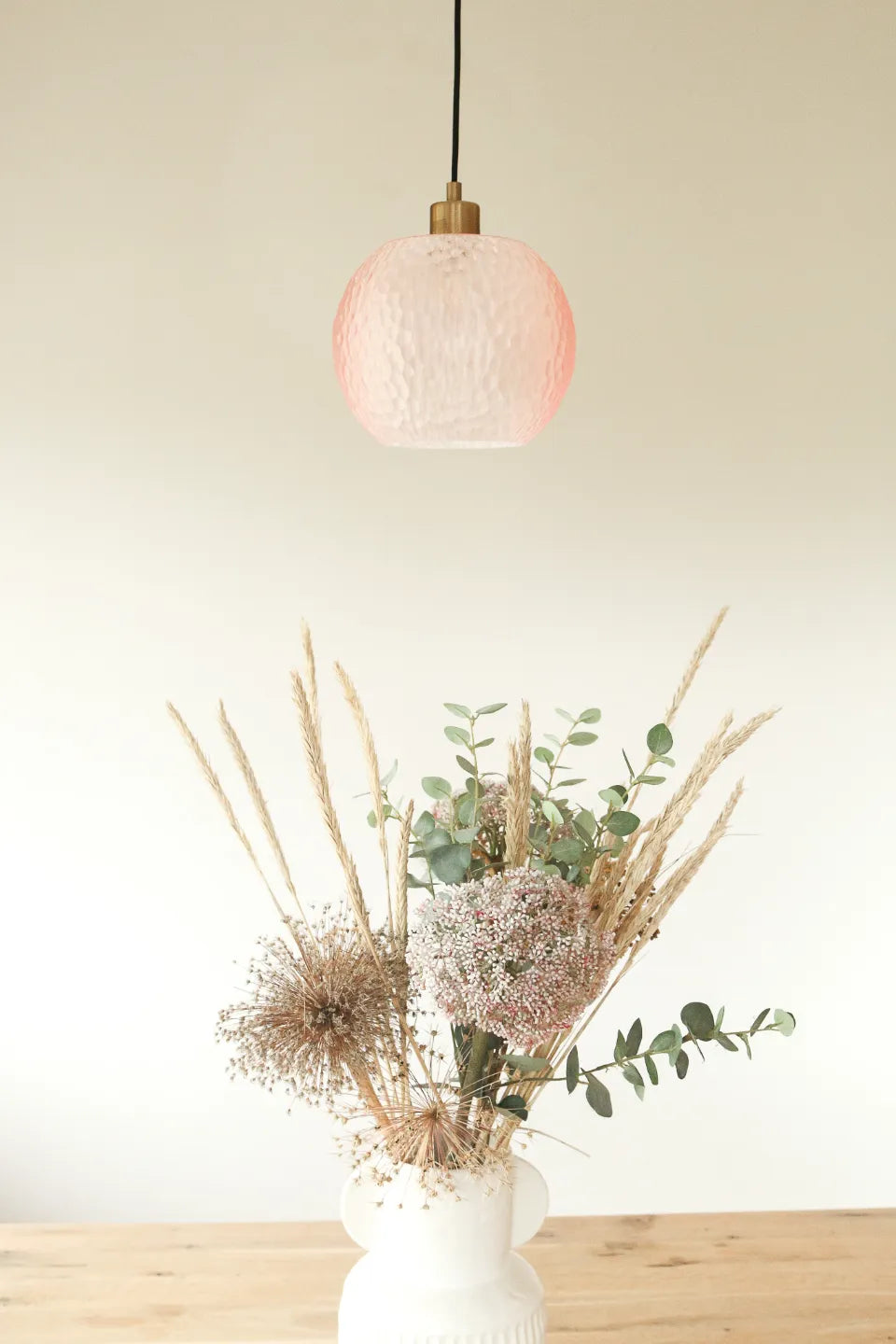 Suspension Rosée présentée au-dessus d’un bouquet décoratif