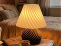 Luminaire Hélice mis en scène sur une table près d’un lit