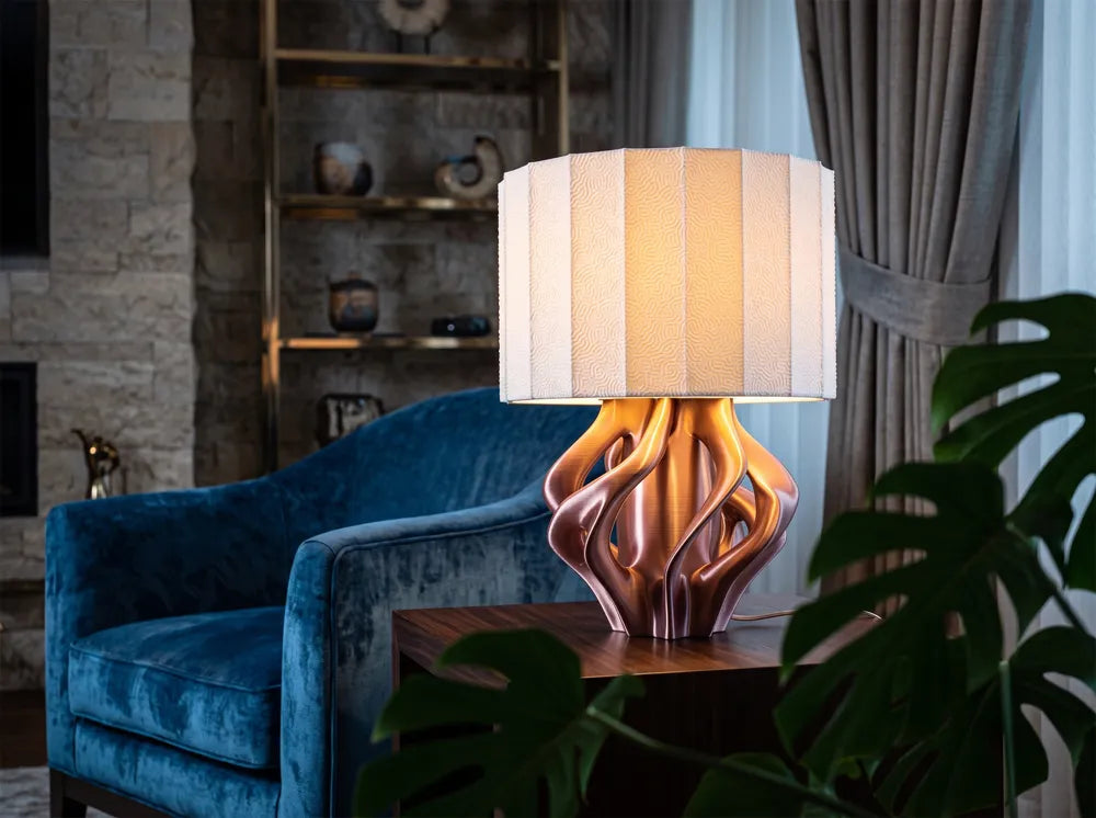 Luminaire Sillage au pied aux reflets cuivrés près d’un fauteuil bleu
